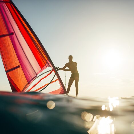 Young man balancing on windsurf board. Windsurfing, sailing, surfing, water sports | ©yossarian6 - stock.adobe.com | Mirko Popadic