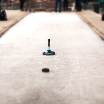 Eistockschießrunde in rustikaler Ambiente: Ein blauer Eisstock nähert sich der Daube | © Mikhail Istratov | Mikhail Istratov