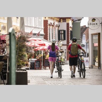 Pärchen spaziert mit Fahrrädern durch die Fußgängerzone von Hartberg | ©  Oststeiermark Tourismus | Velontour
