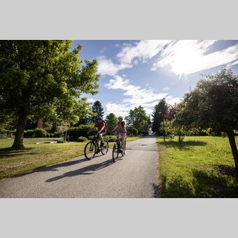 Pärchen fährt mit dem Fahrrad durch die Parkanlage vom Hotel Steirerrast in Kaindorf | © Oststeiermark Tourismus | Velontour