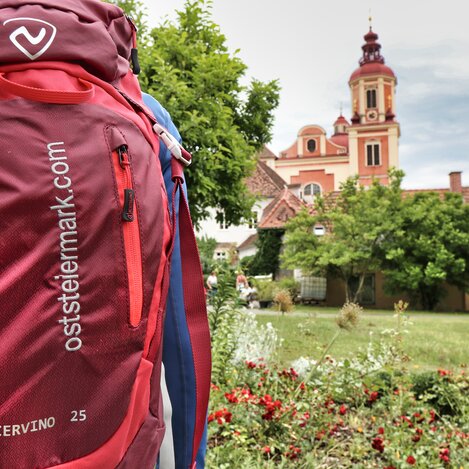Oststeiermark-Rucksack vor der Pfarrkirche Pöllau | © TV Oststeiermark | WEGES OG