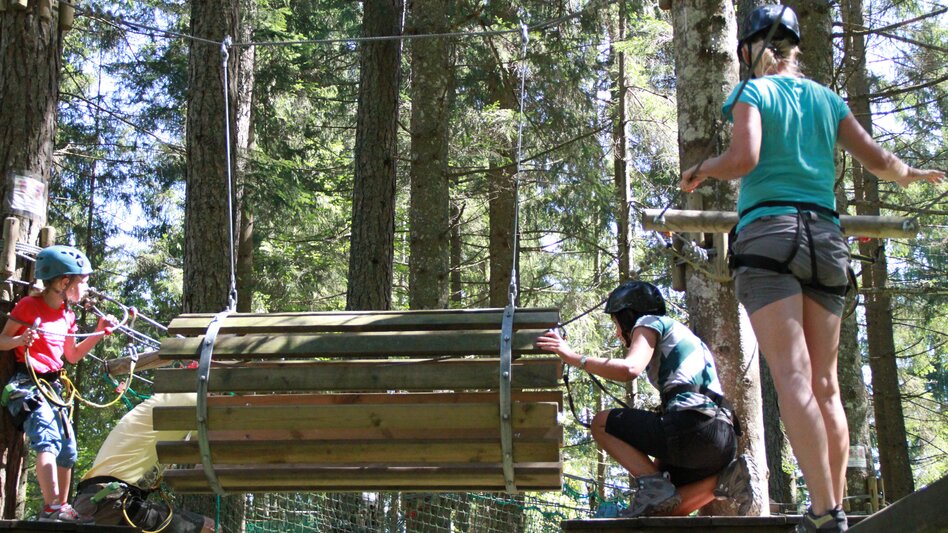 3 Personen im Klettergarten beim Überwinden von einem Hindernis