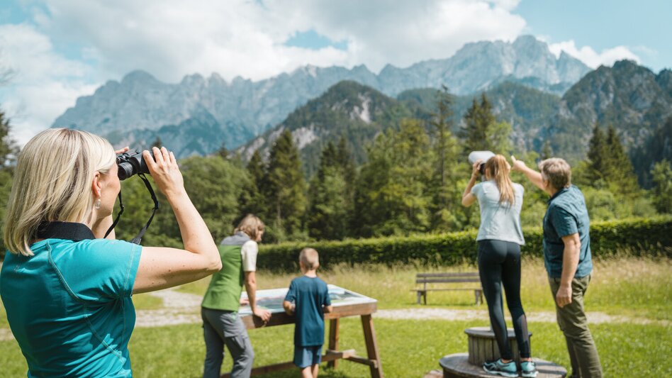 Gruppe mit Ferngläsern vor bergiger Landschaft