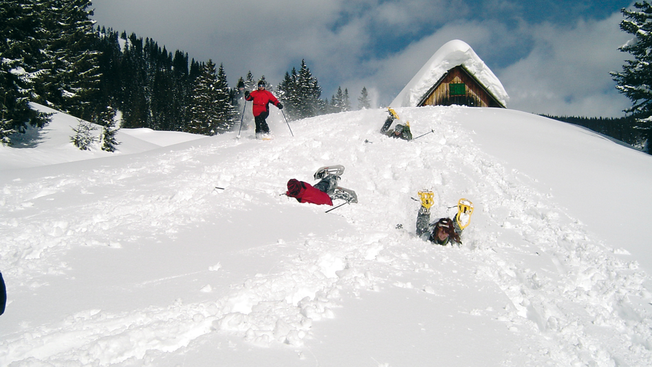 Gruppe beim Schneeschuhwandern im Schnee liegend
