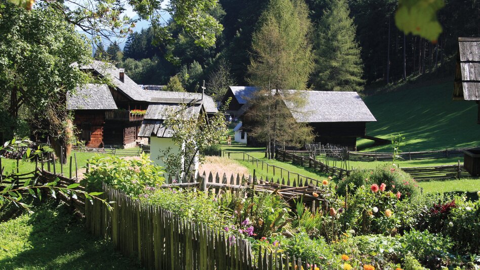 Bunter Bauerngarten mit Bauernhäusern im Hintergrund