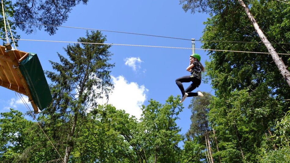 Kind im Hochseilklettergarten auf Flying Fox
