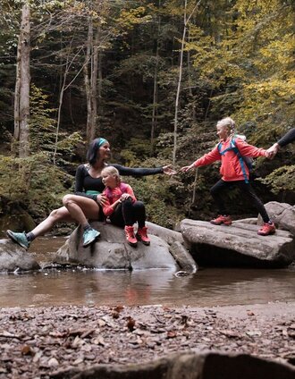 Familie auf Steinen im Bach bei einer Wanderung im Wald | Nadine Geuter | © TVB Südsteiermark/Nadine Geuter