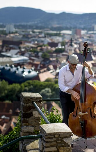 Musician above the roofs of Graz | © Steiermark Tourismus | Tom Lamm