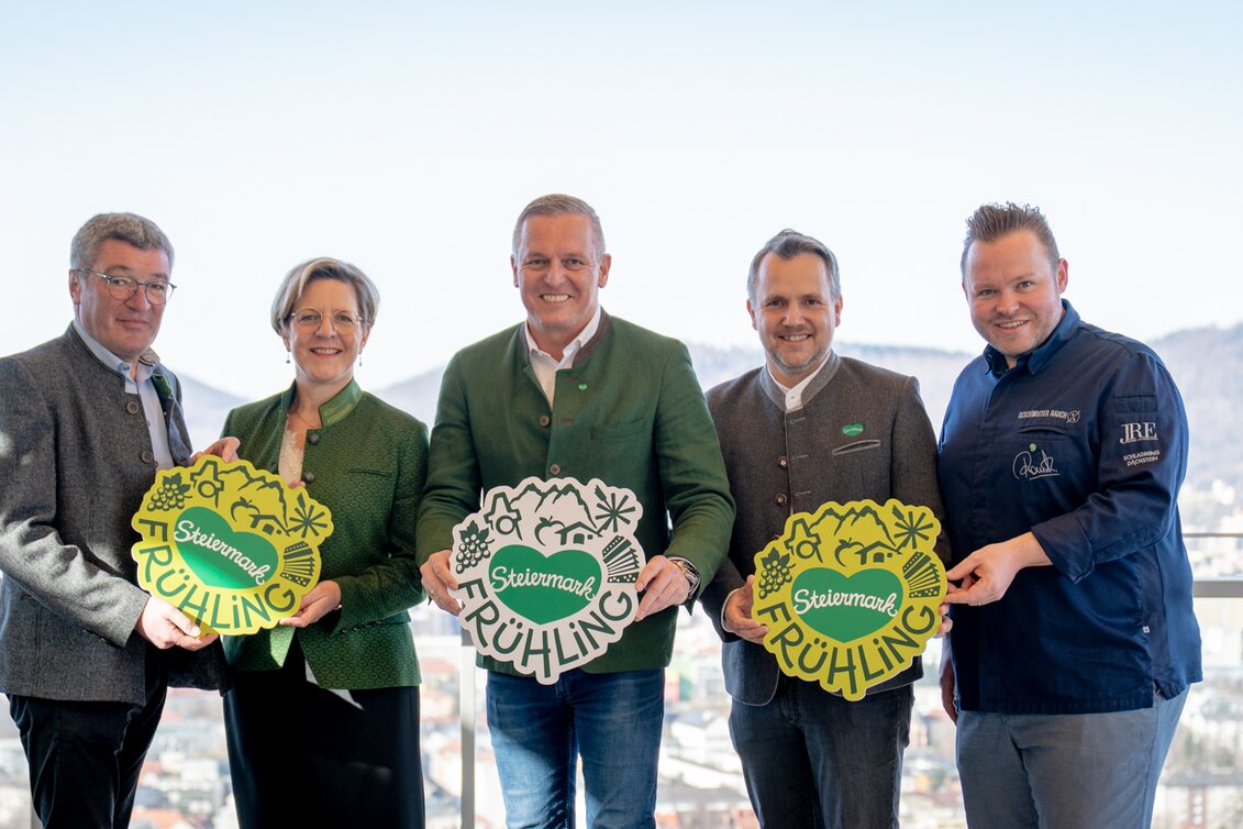 Gruppe von links: Josef Rieberer (GF Brauerei Murau), Evelyn Schweinzger (GF Erlebnisregion Südsteiermark), Landeshauptmann Mario Kunasek, Michael Feiertag (GF STG/Sterische Tourismus und Standortmarketing GmbH) und Sterne- und Haubenkoch Richard Rauch mit neuem Steiermark-Frühling-Logo für den großen Steiermark-Auftritt in Wien bei strahlendem Sonnenschein mit Ausblick über Graz. | © STG | Jaden Gynes
