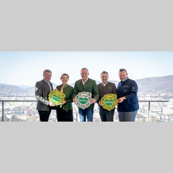 Gruppe von links: Josef Rieberer (GF Brauerei Murau), Evelyn Schweinzger (GF Erlebnisregion Südsteiermark), Landeshauptmann Mario Kunasek, Michael Feiertag (GF STG/Sterische Tourismus und Standortmarketing GmbH) und Sterne- und Haubenkoch Richard Rauch mit neuem Steiermark-Frühling-Logo für den großen Steiermark-Auftritt in Wien bei strahlendem Sonnenschein mit Ausblick über Graz. | © STG | Jaden Gynes