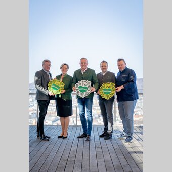 Gruppe von links: Josef Rieberer (GF Brauerei Murau), Evelyn Schweinzger (GF Erlebnisregion Südsteiermark), Landeshauptmann Mario Kunasek, Michael Feiertag (GF STG/Sterische Tourismus und Standortmarketing GmbH) und Sterne- und Haubenkoch Richard Rauch mit neuem Steiermark-Frühling-Logo für den großen Steiermark-Auftritt in Wien bei strahlendem Sonnenschein mit Ausblick über Graz. | © STG | Jaden Gynes