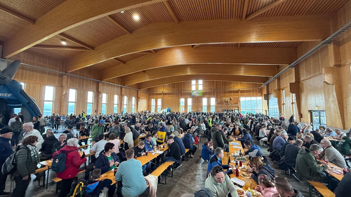 Eine große Menschenmenge in einer gemütlichen Halle mit Holzwänden. Die Gäste sitzen an langen Tischen und genießen ihr Essen. | © SOMA
