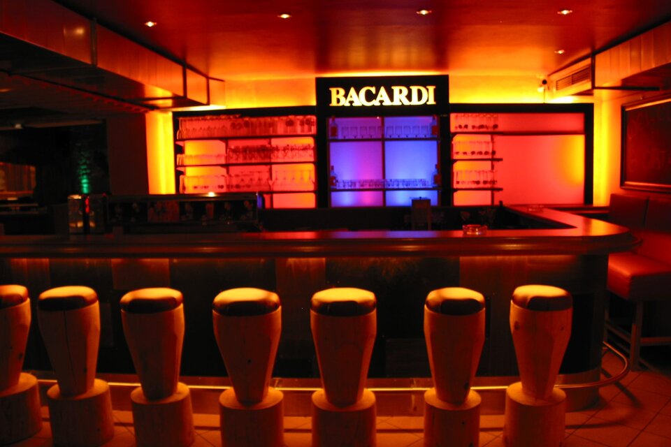 Eine stilvolle Bar mit beleuchteten Regalen und bunten Lichtern. Die Barstühle sind modern und einladend angeordnet. | © Hotel Seebacherhof