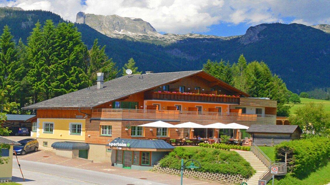 Ein charmantes Hotel in den Bergen mit einer Holzfassade. Die Umgebung ist grün bewachsen und es gibt eine beeindruckende Bergkulisse. | © Hotel Seebacherhof