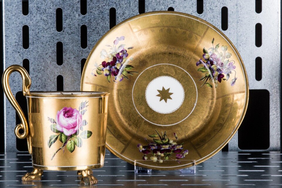 Eine elegante Tasse mit goldener Verzierung und Blumendekoren steht neben einer passenden Untertasse. Beide Teile zeigen kunstvolle Handwerkskunst. | © Markus Mansi_MOMA