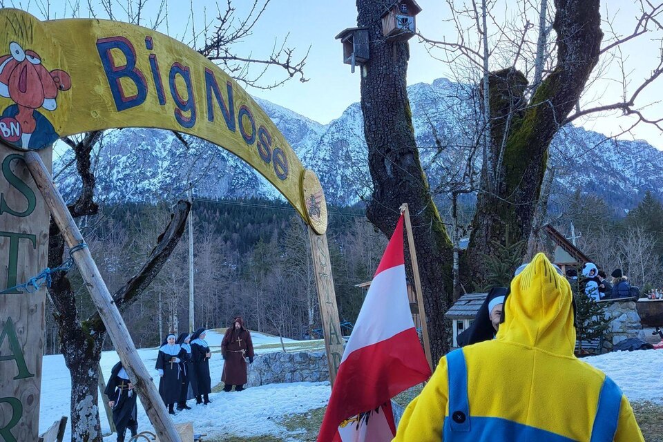 Ein Eingangsschild mit dem Namen "Big Nose" in einer verschneiten Landschaft. Im Hintergrund sind Berge und Menschen in warmer Kleidung zu sehen. | © Petra Kirchschlager