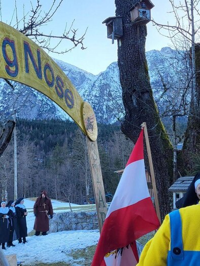 Ein Eingangsschild mit dem Namen "Big Nose" in einer verschneiten Landschaft. Im Hintergrund sind Berge und Menschen in warmer Kleidung zu sehen. | © Petra Kirchschlager