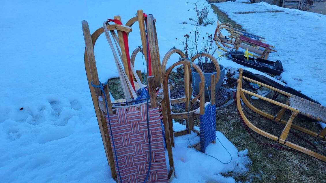 Eine Gruppe von Schlitten steht auf einem schneebedeckten Grundstück. Im Hintergrund sind weitere Schlitten und ein Stück Gras sichtbar. | © Petra Kirchschlager