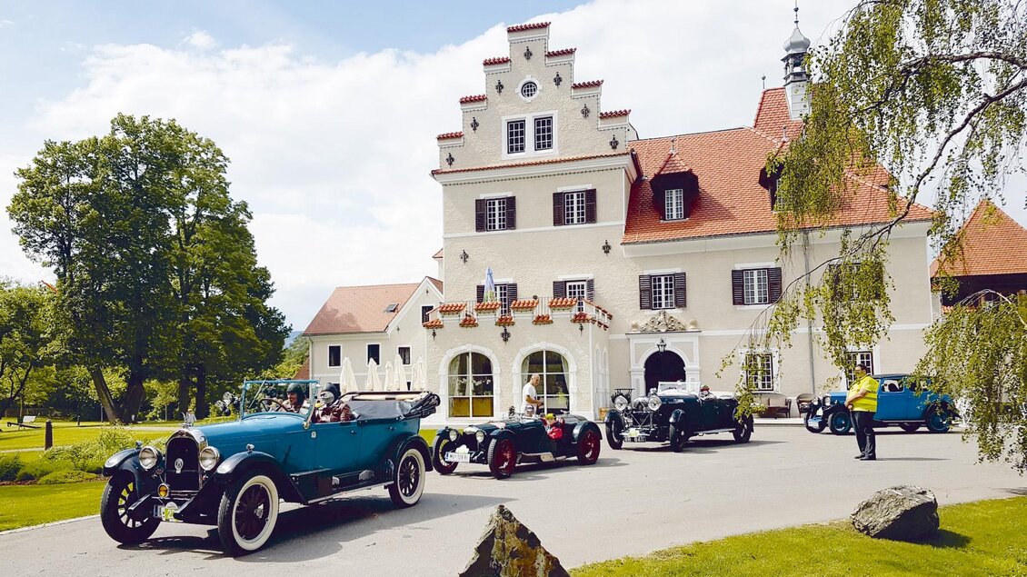 Eine elegante Villa im Hintergrund mit klassischen Autos im Vordergrund. Die Landschaft ist grün und gut gepflegt. | © FHF Murtal Classic