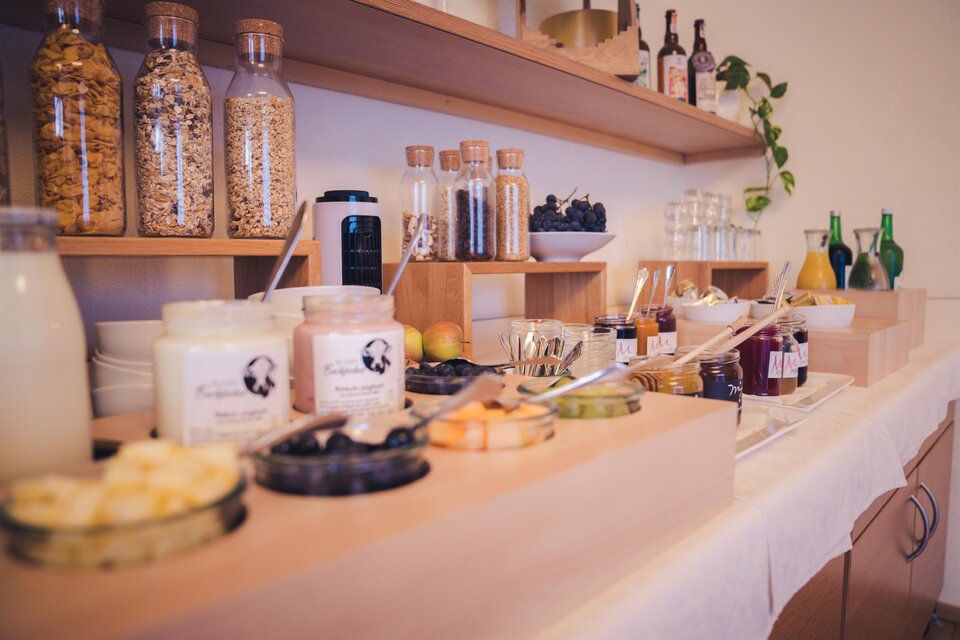 Ein hübsches Buffet mit verschiedenen Lebensmitteln und Getränken. Es gibt Gläser mit Müsli, Joghurt, Obst und Säfte. | © Martinhof