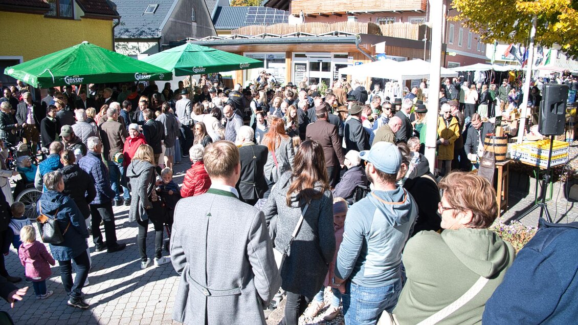 Eine große Menschenmenge versammelt sich auf einem Platz mit Bäumen und Zelten. Die Stimmung ist lebhaft und fröhlich. | © Echtzeit TV