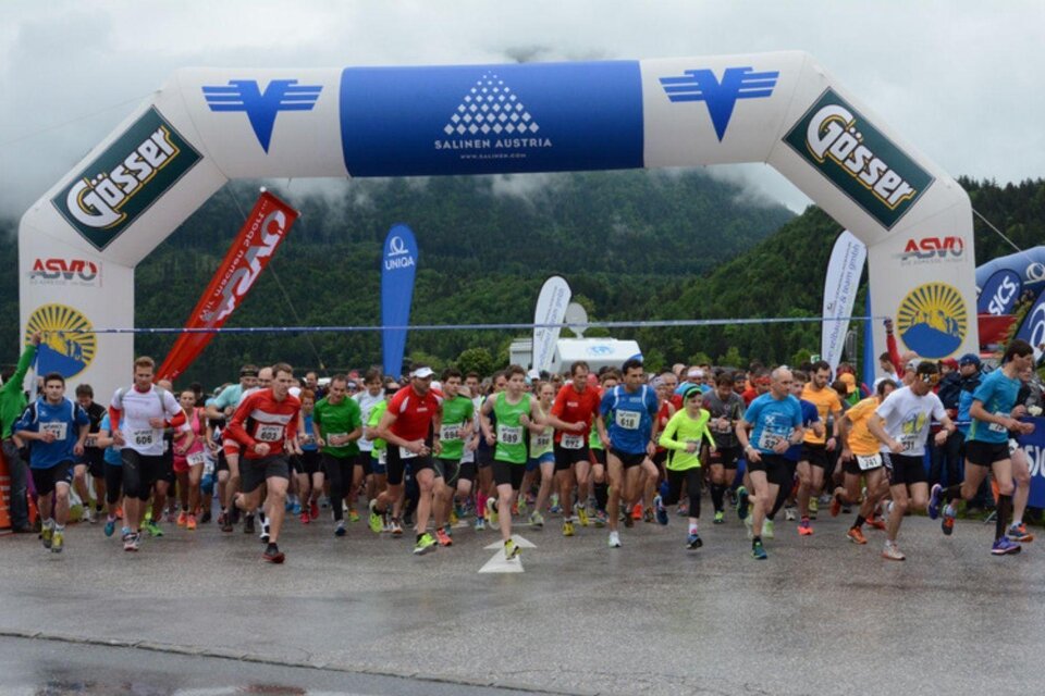 Eine Gruppe von Läufern startet einen Wettlauf unter einem großen Startbogen. Im Hintergrund sind Bäume und Banner zu sehen, die die Veranstaltung kennzeichnen. | © Gunter Schafhuber