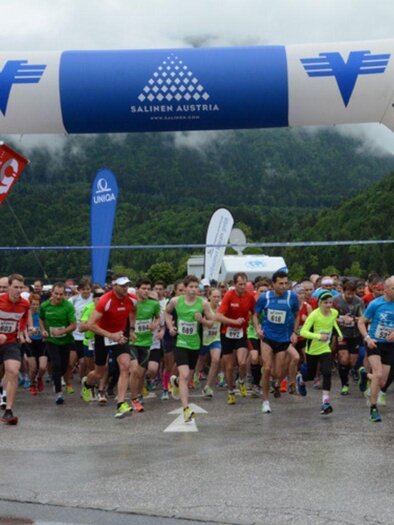 A group of runners starts a race under a large starting arch. In the background, there are trees and banners marking the event. | © Gunter Schafhuber