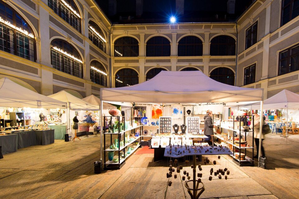 Ein nächtlicher Markt mit weißen Zelten und bunten Ständen. Besucher schauen sich handgefertigte Kunstwerke und Dekorationen an. | © graz toursimus- -Harry Schiffer