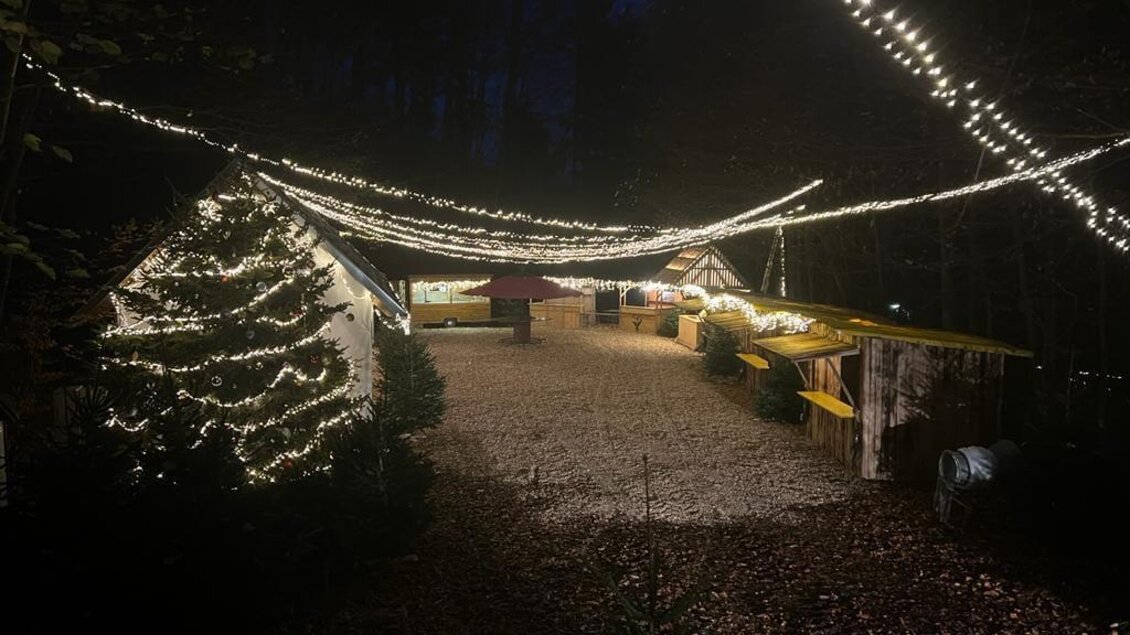Ein festlich dekorierter Markt im Wald, beleuchtet von vielen Lichtern. Die Stände sind festlich geschmückt und schaffen eine gemütliche Atmosphäre. | © Brauchtumsverein_St.Andrä-Höch
