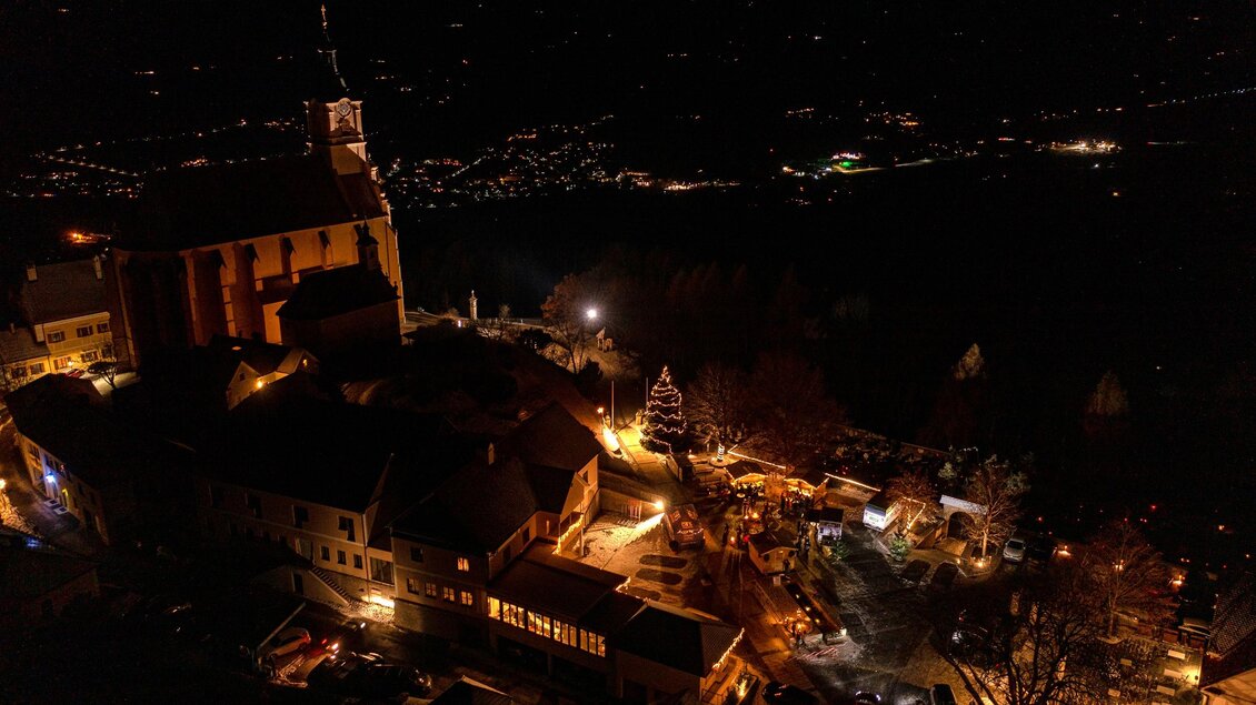 Eine malerische Stadtansicht bei Nacht mit beleuchteten Gebäuden und einer Kirche. Der Himmel ist dunkel, und die Lichter der Umgebung schaffen eine gemütliche Atmosphäre. | © ©Rene Strasser