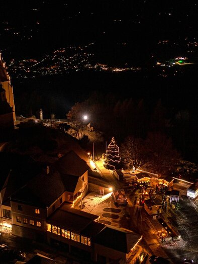 A picturesque view of the town at night with illuminated buildings and a church. The sky is dark, and the lights of the surroundings create a cozy atmosphere. | © ©Rene Strasser