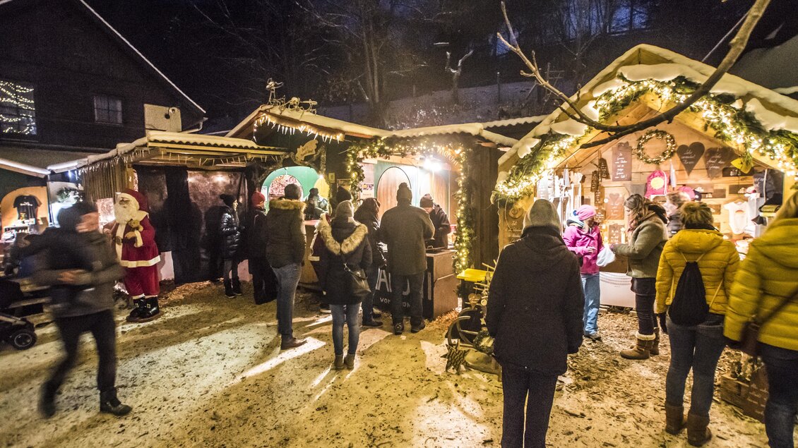 Ein festlicher Weihnachtsmarkt mit vielen Menschen in warmen Winterkleidung. Stände sind weihnachtlich dekoriert und es herrscht eine gemütliche Atmosphäre. | © Gerhard Pilz