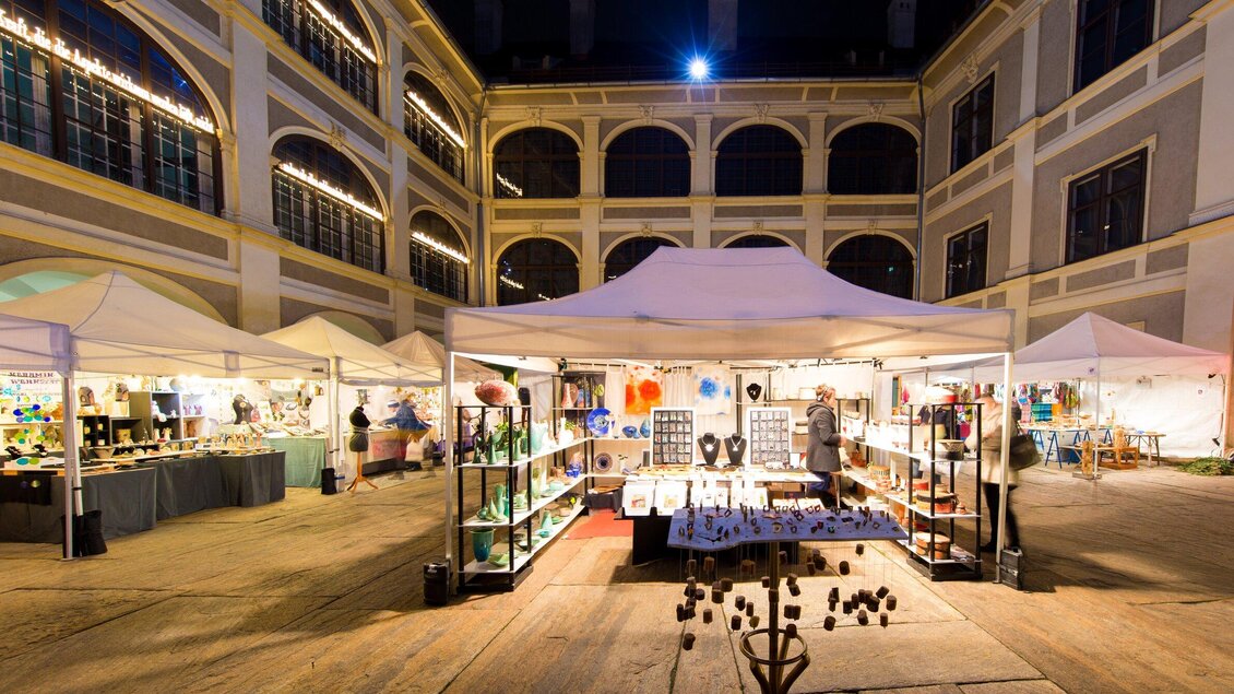 Ein belebter Markt mit mehreren Verkaufsständen unter Zelten. Die Atmosphäre ist festlich mit Beleuchtung und Leuten, die sich umsehen. | © Graz Tourismus - Harry Schiffer