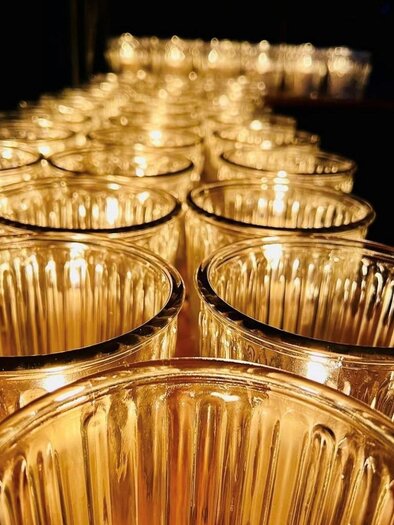 Eine Reihe von transparenten Gläsern, die sanft leuchten. Die Gläser sind in einem dunklen Raum angeordnet und schaffen eine warme Atmosphäre. | © Rainer Böhm