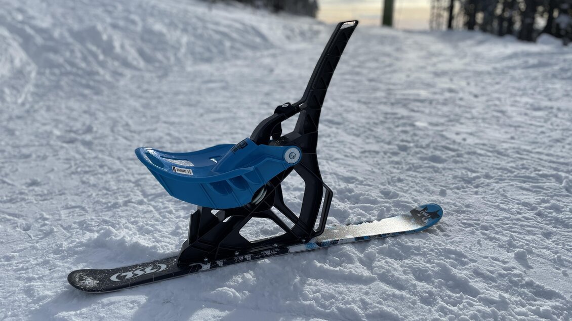 Ein blauer Schlitten steht auf der verschneiten Piste. Im Hintergrund sind schneebedeckte Bäume sichtbar. | © Steirisch Wandern