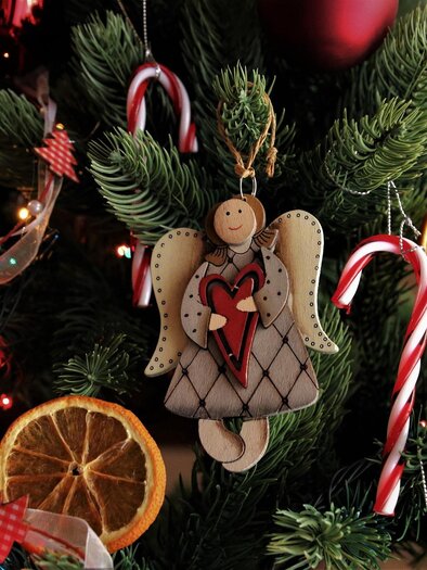 A decorated Christmas tree with colorful ornaments and lights. An angel with a red heart hangs from the branches. | © pixabay.com