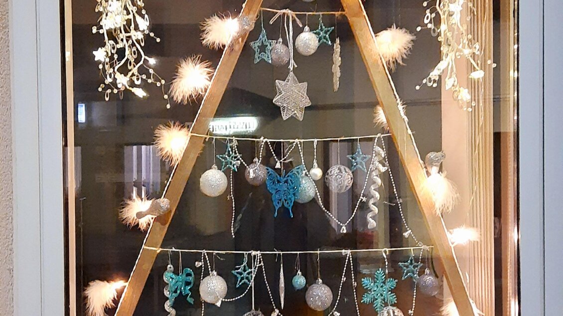 Ein schön dekoriertes Fenster mit einem Weihnachtsbaum aus Holz. Der Baum ist mit Lichtern und festlichen Ornamenten geschmückt. | © Thermen- & Vulkanland/ Sabrina Halbedl