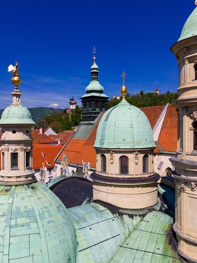 A view of the distinctive towers with green domes and golden weather vanes. The buildings are surrounded by a clear blue sky. | © Graz Tourismus-Harry Schiffer