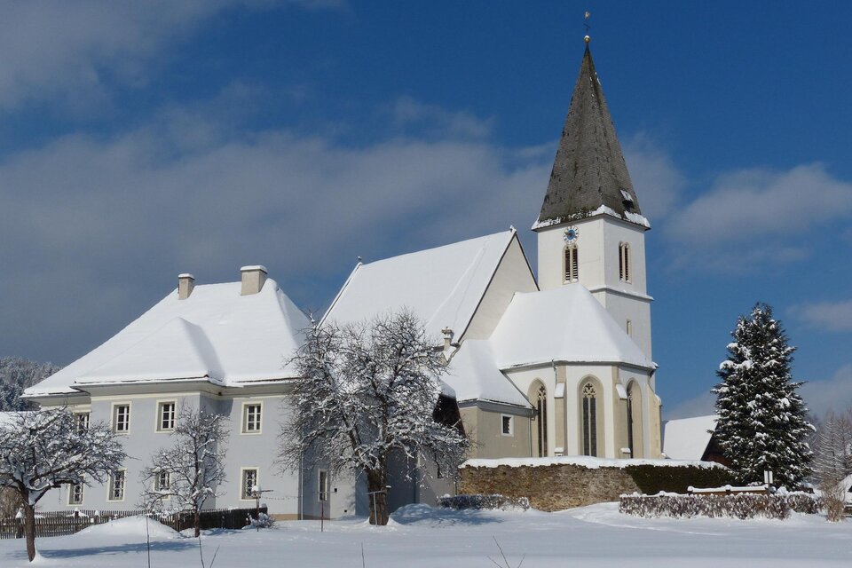 Eine verschneite Landschaft mit einem hübschen Gebäude und einer Kirche. Der Himmel ist klar und blau. | © Gemeinde Hirschegg-Kopp Josef