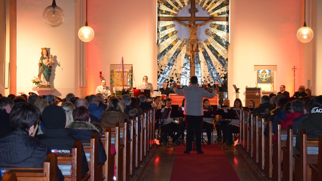 Eine volle Kirche während eines Konzerts. Im Hintergrund ist ein großes Kreuz und die Bühne ist stimmungsvoll beleuchtet. | © Stadtgemeinde Bärnbach