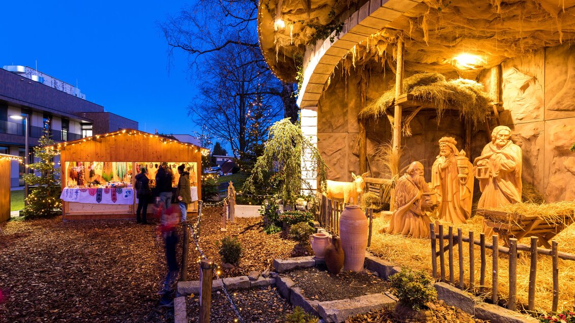 Ein stimmungsvolles Weihnachtsmarkt mit illuminierter Krippe und Ständen. Bunte Lichter und eine festliche Atmosphäre umgeben die Besucher. | © TV Region Graz-Harry Schiffer