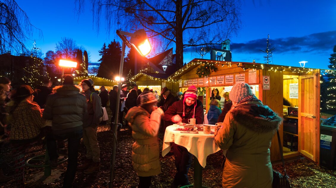 Ein winterlicher Markt mit festlich beleuchteten Ständen und einer lebhaften Menschenmenge. Die Atmosphäre ist gemütlich und einladend bei Nacht. | © TV Region Graz-Harry Schiffer