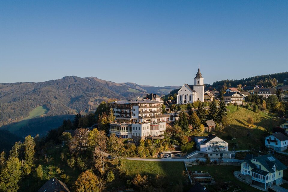 Ein malerisches Dorf auf einem Hügel mit einer Kirche und mehreren Häusern. Die umliegenden Berge und die klare Himmelbt zeichnen eine ruhige Landschaft. | © Der WILDe EDER
