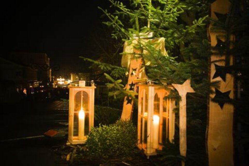 Lampen in Laternen leuchten in der Dunkelheit neben einem Weihnachtsbaum. Im Hintergrund sind festliche Lichter sichtbar. | © TVB Thermen- 6 Vulkanland