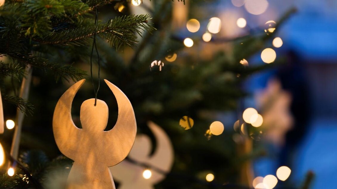 Ein geschmückter Weihnachtsbaum mit bunten Lichtern und Holzanhängern in Form von Engeln. Die festliche Atmosphäre wird durch das sanfte Licht unterstrichen. | © TV Thermen- & Vulkanland