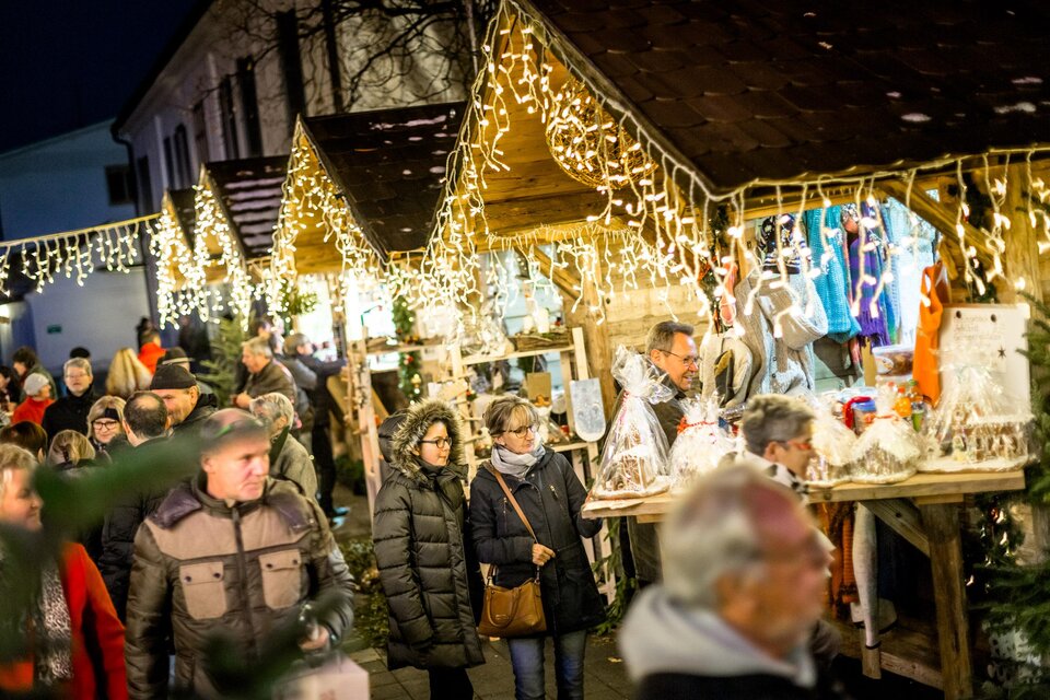 Ein festlicher Weihnachtsmarkt bei Nacht, beleuchtet mit strahlenden Lichtern. Menschen schlendern zwischen kunsthandwerklichen Ständen und genießen die Atmosphäre. | © TVB Südsteiermark