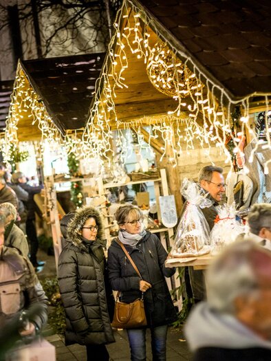 Ein festlicher Weihnachtsmarkt bei Nacht, beleuchtet mit strahlenden Lichtern. Menschen schlendern zwischen kunsthandwerklichen Ständen und genießen die Atmosphäre. | © TVB Südsteiermark