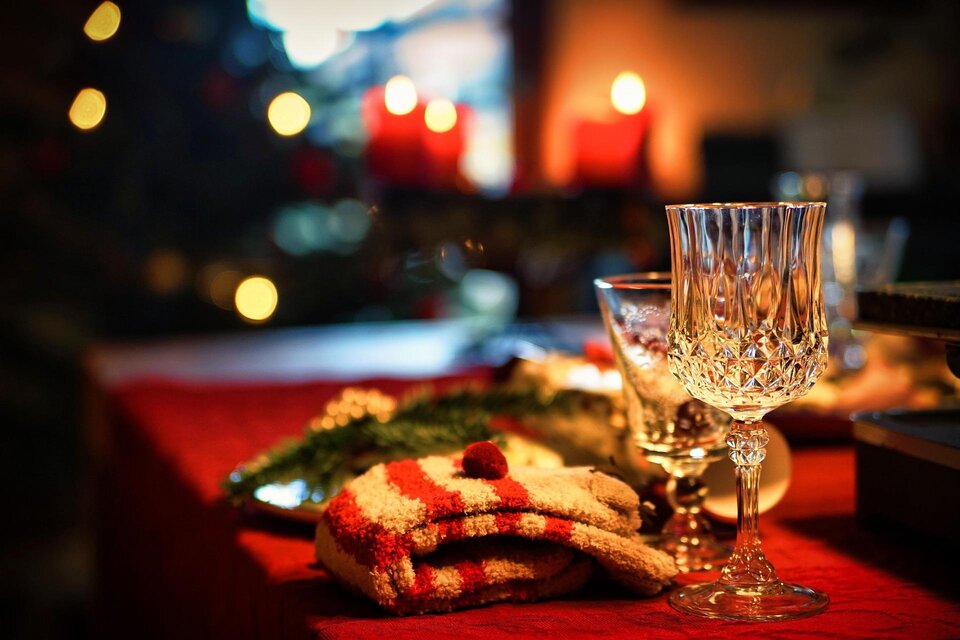 Ein festlich gedeckter Tisch mit gläsernen Bechern und weihnachtlichen Dekorationen. Im Hintergrund leuchten Kerzen und ein Weihnachtsbaum. | © pixabay.com