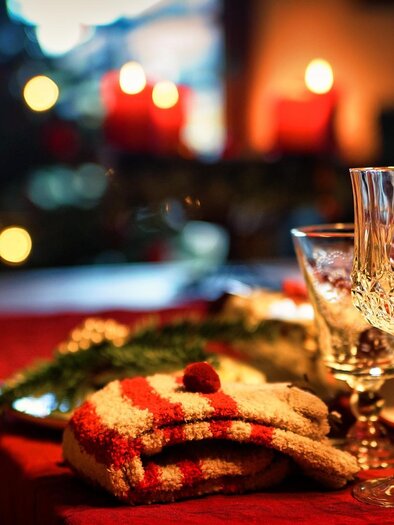 A festively set table with glass cups and Christmas decorations. In the background, candles and a Christmas tree are glowing. | © pixabay.com