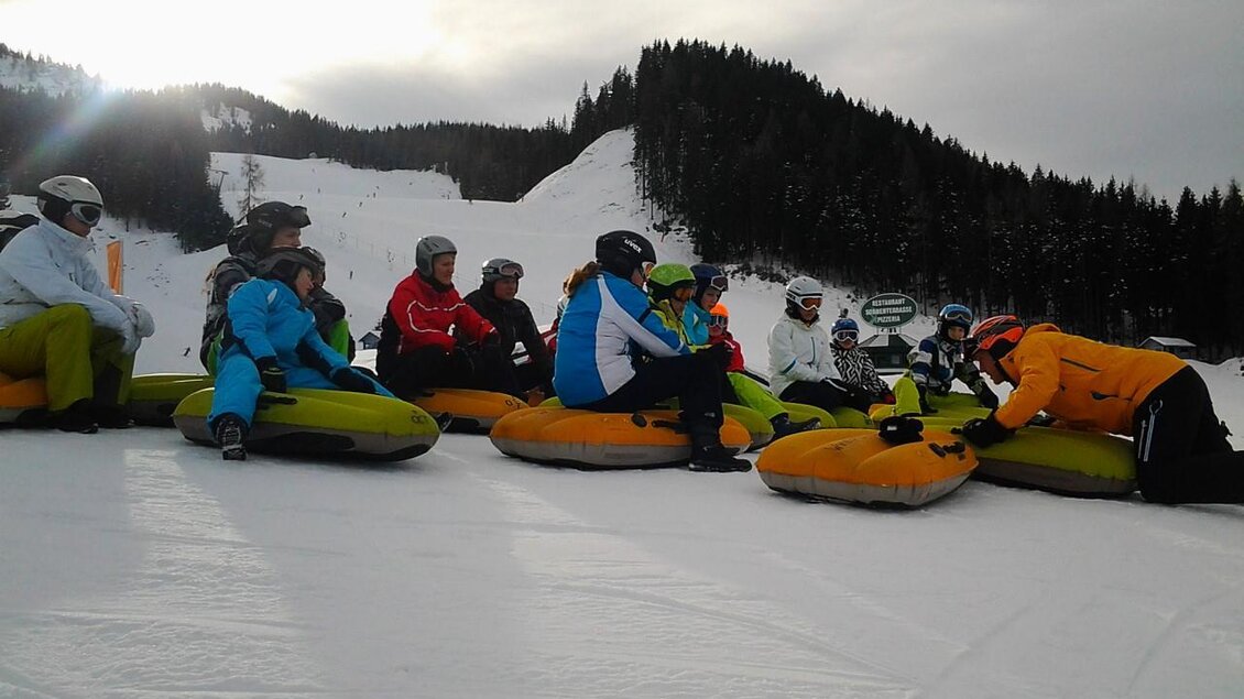 Eine Gruppe von Menschen sitzt auf Schlitten im Schnee. Sie tragen Wintersportkleidung und genießen die kalte, klare Umgebung. | © OCT